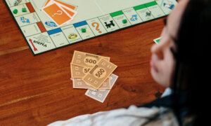 Woman playing a game of Monopoly, wondering how their credit score could affect hers.