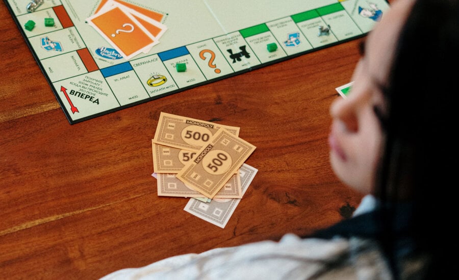 Woman playing a game of Monopoly, wondering how their credit score could affect hers.