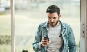 Canadian using his cell phone to check our Best robo-advisors in Canada ranking for 2024.