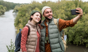 A young man and woman take a selfie by a river