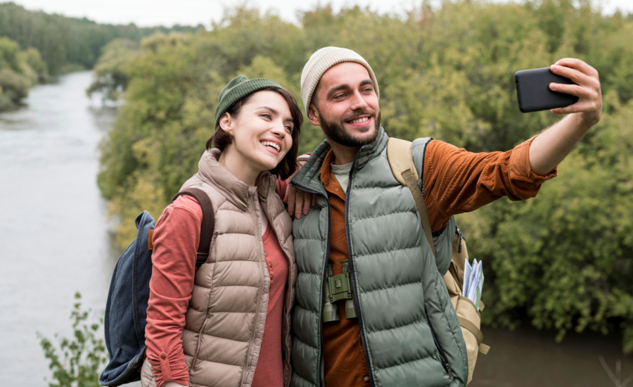 A young man and woman take a selfie by a river