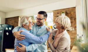 Happy senior parents and their adult son having fun while greeting in the kitchen.