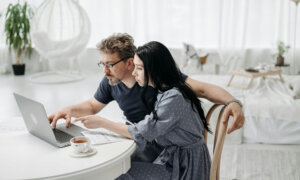 A man and a woman in their 40s, looking at their respective retirement plans on a laptop.