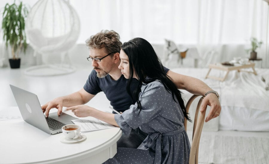 A man and a woman in their 40s, looking at their respective retirement plans on a laptop.