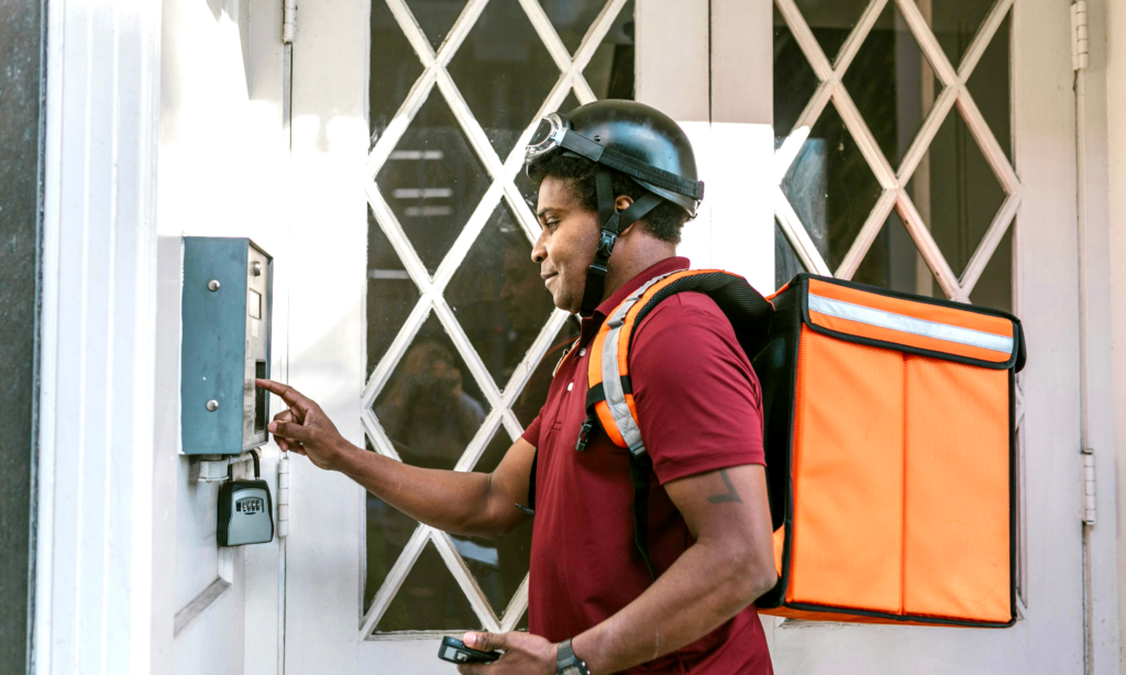 A food delivery courier rings the buzzer at an apartment building