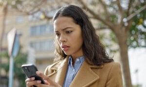 Woman, looking at her phone wondering, "Can I get scammed through e-transfer?"
