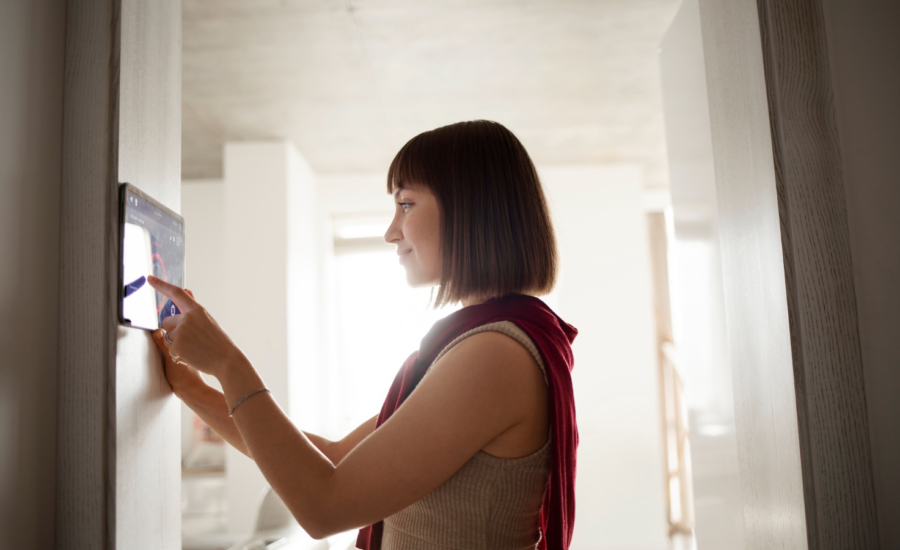 A young woman adjusts the temperature on a home thermostat