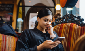 A young Indian woman reads on her phone in a cafe