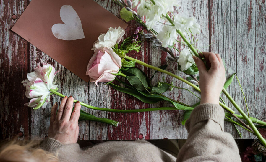 Woman putting together a bouquet with flowers she bought at a supermarket.