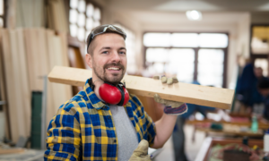 A contractor holds a two by four on a job site