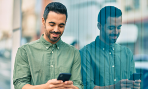 A man smiles as he checks his phone