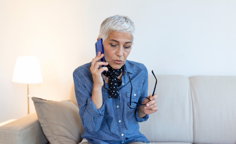 A woman listens to a scam call on her phone