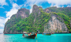 Three boats besides a cliff face in Maya Bay in Thailand