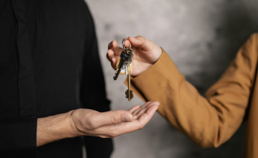 A person is seen handing keys to a house to another person.