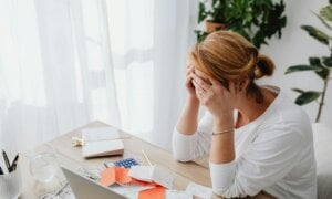 A women looking over at a desk with a laptop and has her hands clasped.
