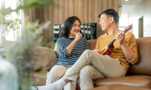 A senior couple sing and play ukulele in their living room