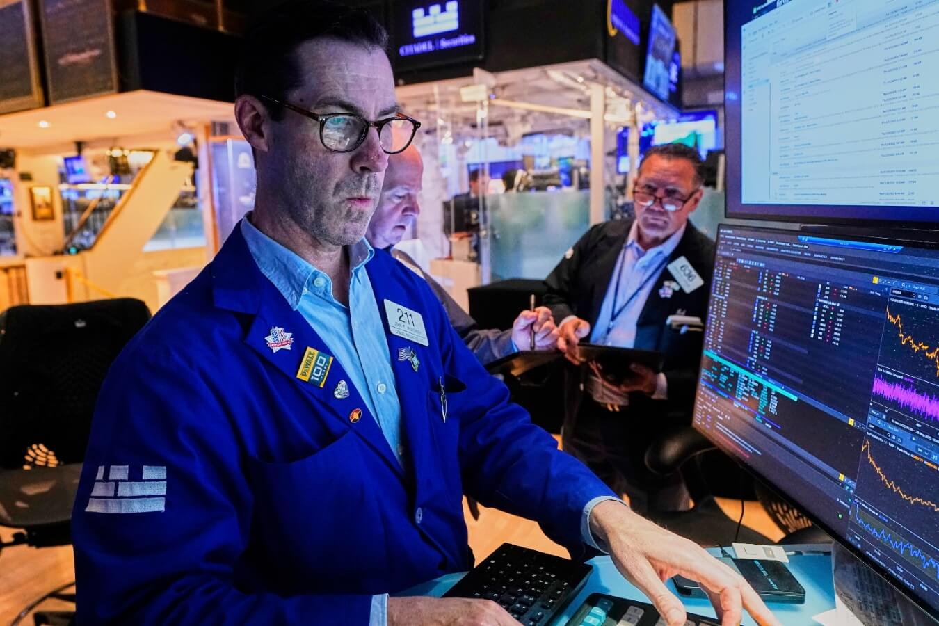Specialist John McNierney, left, works with traders on the floor of the New York Stock Exchange