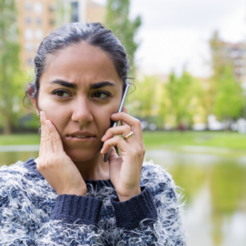 A worried-looking young woman talks on her phone