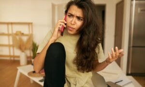 A woman is seen talking on the photo with a confused look on her face.