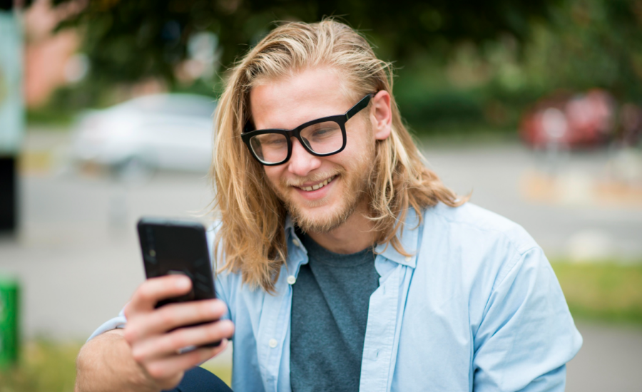 Smiling young man checks his crypto portfolio on his phone