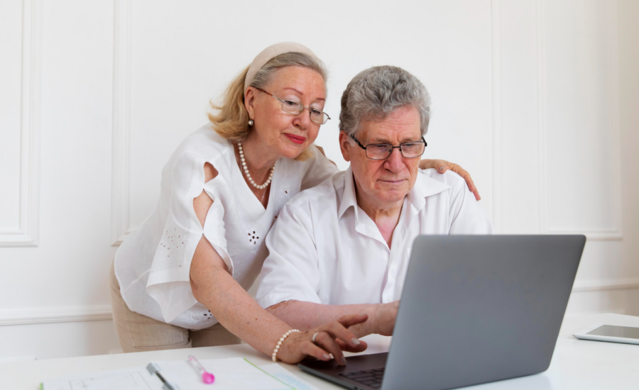 A senior-age man and woman check their financial accounts on a laptop