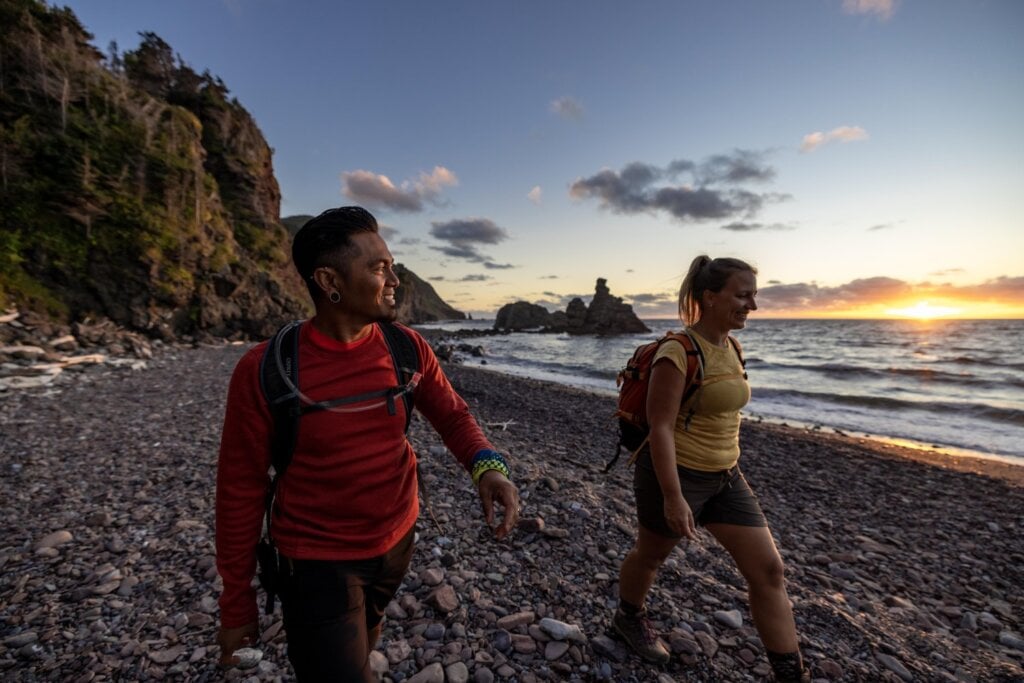 Um homem e uma mulher caminhando em uma praia rochosa