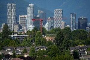 A crane is seen above a wood-frame condo project under construction as condo and office towers line the downtown skyline, in Vancouver, on Friday, July 4, 2025. While optimism is building in some parts of Canada for a second-half rebound in the real estate market, condominium dwellers aiming to move up to a larger space face tough choices amid little sign of improvement for that segment.