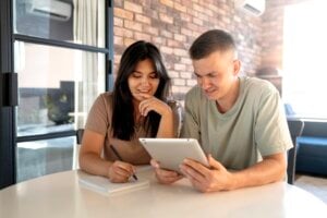 A young man and woman take notes and look at a tablet