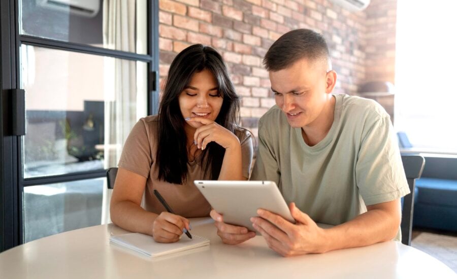 A young man and woman take notes and look at a tablet