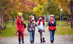 Four young kids walking to school in the fall