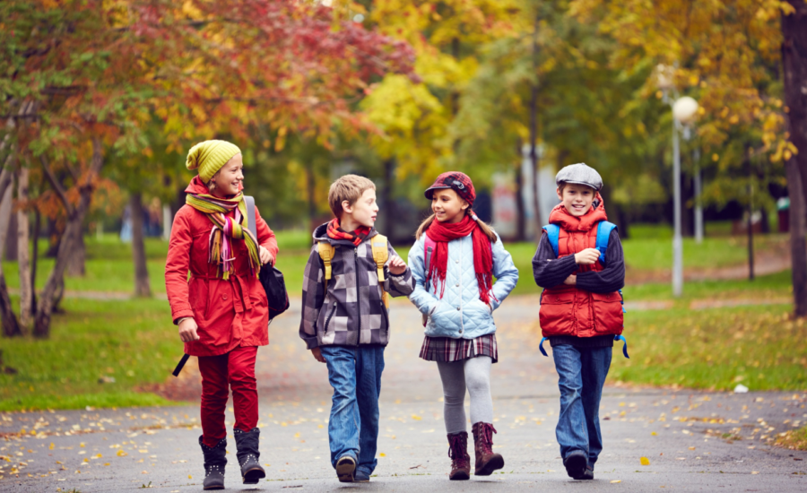 Four young kids walking to school in the fall