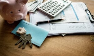 House keys, a calculator, and paperwork laying on a desk.