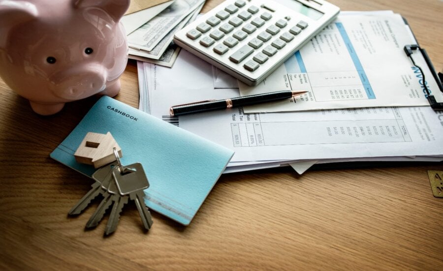 House keys, a calculator, and paperwork laying on a desk.