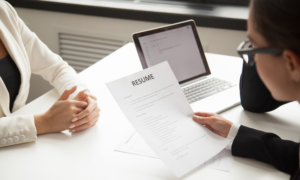 A recruiter looks at a job applicant's resume during an interview