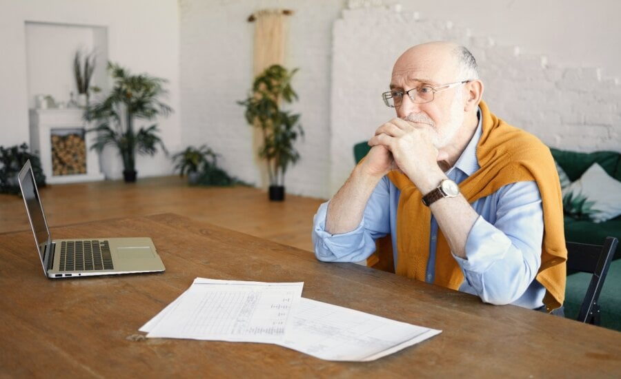 Senior man sitting at a desk with papers, looking serious