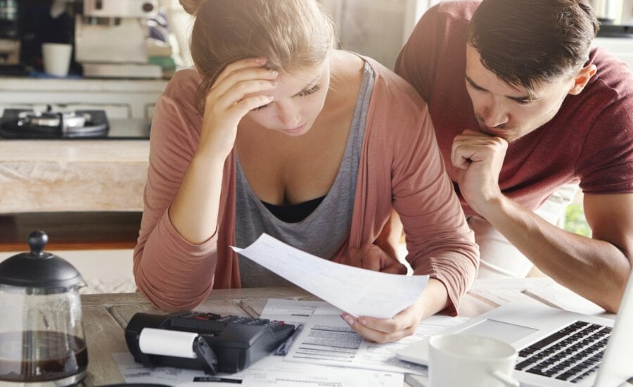 Young couple budgeting at a desk with papers and a calculator