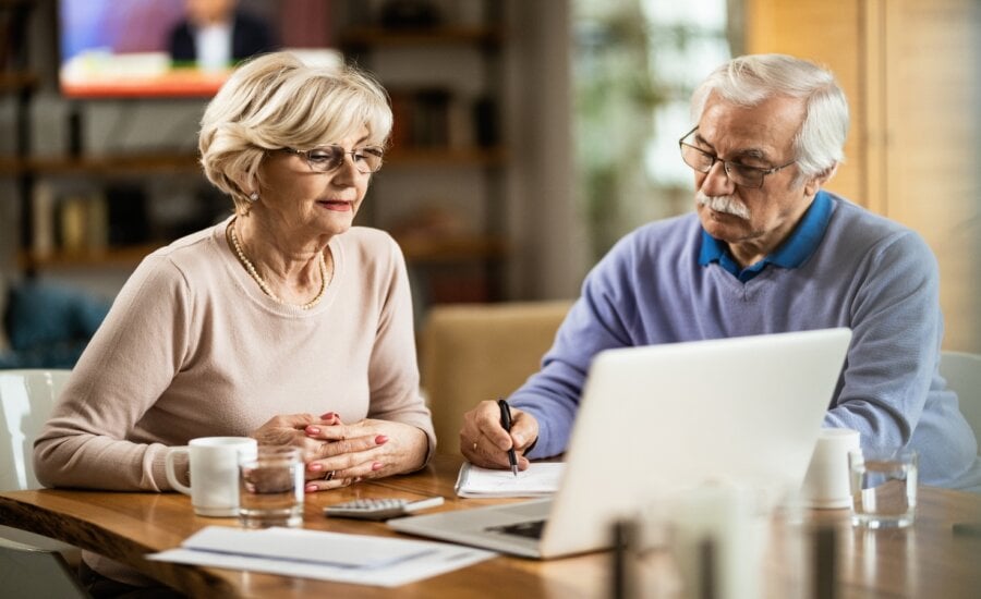 Senior couple sitting at a desk with a laptop working on finances
