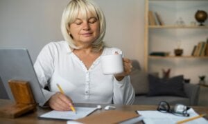Senior woman at a desk holding a cup of coffee