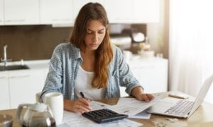 Picture of young Caucasian woman wearing casual clothes at home, full of sad and restless thoughts, feeling stressed calculating her debts for rent and making notes, surrounded with papers and gadgets SSUCv3H4sIAAAAAAAEAJ2RQW7DIBBF95V6B4u1LRljk6ZXiboYw9QdhZgKcKoo8t0DxpZYV2LBf8OH+cPz/a2q2AieFPusnklFTcYsPjgIZOeI23rnqClYR2ASTGzdKswHCItHn67YkYKAUzyb4e4/3rlkXR2FrRgdscRYXTC/jBs70Fr/25k3X0cUmHBWj63hIohDg5CDXPJRdv0L6G5ltDtptIWGRZMtUt6tApMMorj515GieSpsNvygKycWR25vBZht2DrZgzEdR5okF7yX577rh4+4BBeSHd9g1ZV02Svp5Gh7OXTipJtuULrpOWAzIkCjuGzl6TxyGL/jpNYXk32JqA4CAAA=