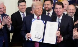President Donald Trump, center, surrounded by House Majority Whip Tom Emmer, R-Minn., from left, Rep. Bryan Steil, R-Wis., Vice President JD Vance, Sen. Bill Hagerty, R-Tenn., and Commerce Secretary Howard Lutnick, holds up the GENIUS Act, a bill that regulates stablecoins, a type of cryptocurrency, after he signs the bill in the East Room of the White House, Friday, July 18, 2025, in Washington.