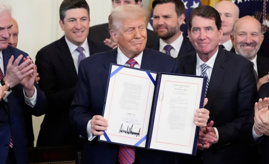 President Donald Trump, center, surrounded by House Majority Whip Tom Emmer, R-Minn., from left, Rep. Bryan Steil, R-Wis., Vice President JD Vance, Sen. Bill Hagerty, R-Tenn., and Commerce Secretary Howard Lutnick, holds up the GENIUS Act, a bill that regulates stablecoins, a type of cryptocurrency, after he signs the bill in the East Room of the White House, Friday, July 18, 2025, in Washington.
