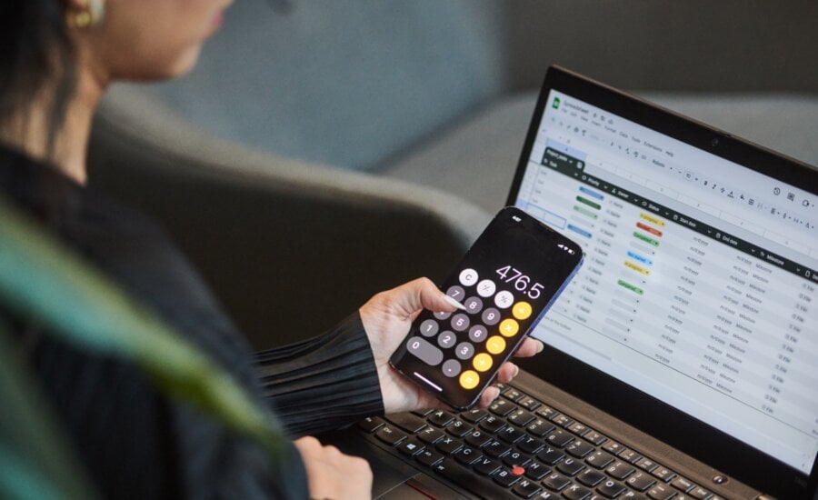A person uses the calculator app on their phone and works on a spreadsheet in a photo illustration made in Toronto, on Monday, Sept. 22, 2025.