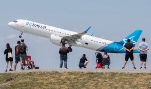 People look on as an Air Transat plane takes off at Trudeau in Montreal, Sunday, June 11, 2023. Signs warning people that the consumption of food is prohibited have been erected at Jacques de Lesseps plane spotting park to deter the gathering of birds. THE CANADIAN