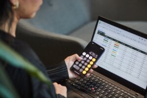 A person uses the calculator app on their phone and works on a spreadsheet in a photo illustration made in Toronto, on Monday, Sept. 22, 2025.