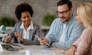 Couple using a tablet while in a meeting with a banking professional.