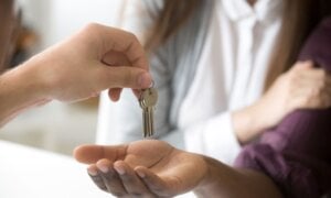 Person handing a couple a key for a house