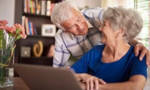 Senior couple smiling and looking at a computer