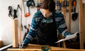 Woman in safety glasses working at a workshop table.