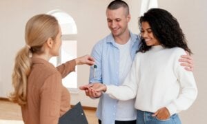 Young couple receiving keys to a new home from a real estate agent.