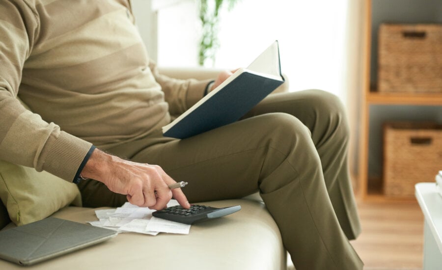 Cropped image of aged man checking his bills and credit payments